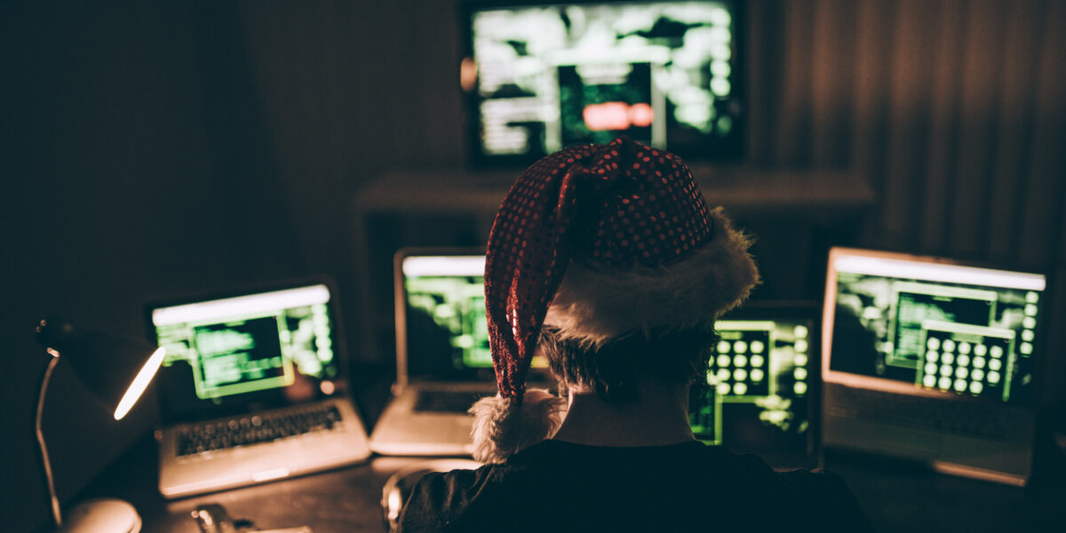 Computer hacker wearing santa hat while working on laptop late at night