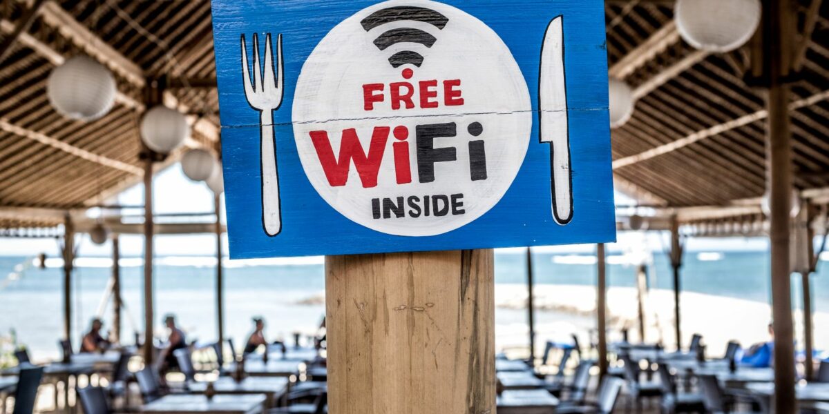 a painted sign on a pillar in a beach restaurants advertising free public Wi-Fi inside.