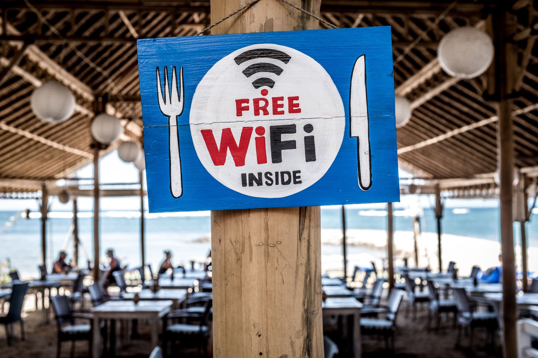 a painted sign on a pillar in a beach restaurants advertising free public Wi-Fi inside.