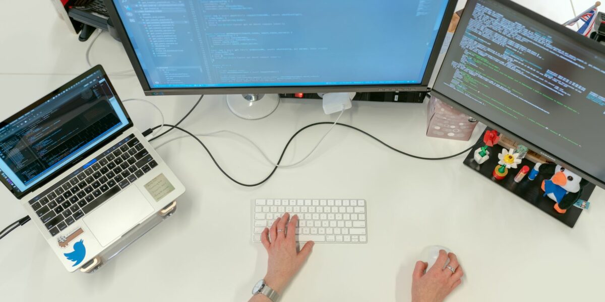 An IT worker setting up synchronization between two desktop and one laptop for a company's data recovery plan.