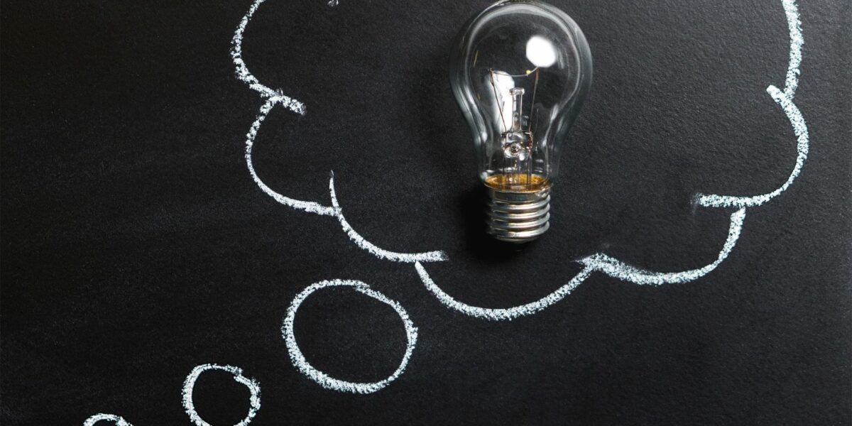 A chalk board with three white circles leading to a larger fluffy cloud with a lightbulb in the center to represent cloud services.