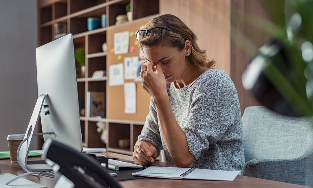 woman sitting at a desk frustrated by her computer performance failure.