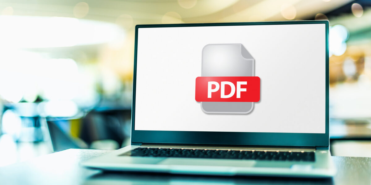 A lap top on a desk with a PDF document icon to represent ways to convert documents to PDF