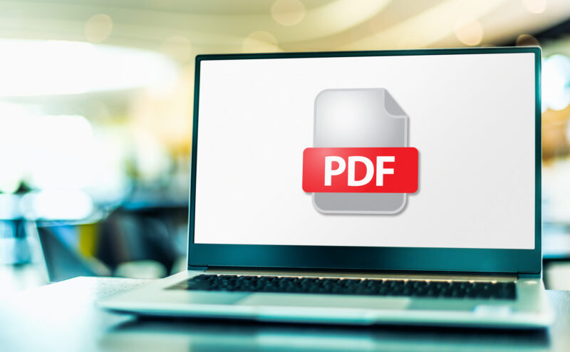 A lap top on a desk with a PDF document icon to represent ways to convert documents to PDF
