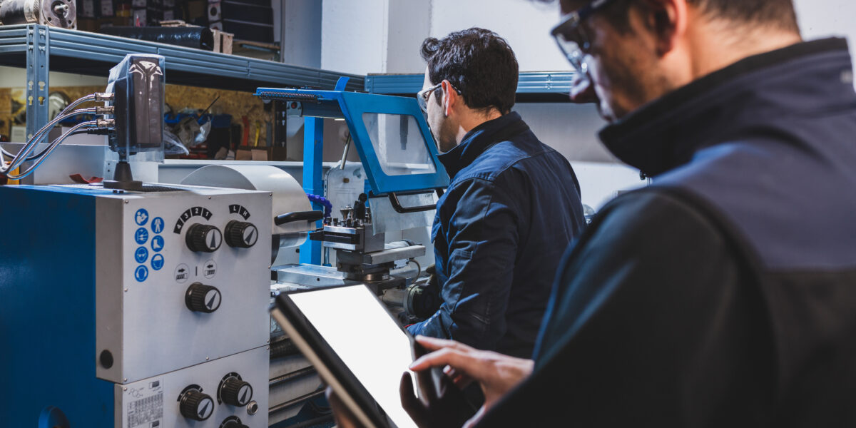 an image representing IT services for manufacturing by showing an IT specialist working along side a manufacturing personal to review their data.